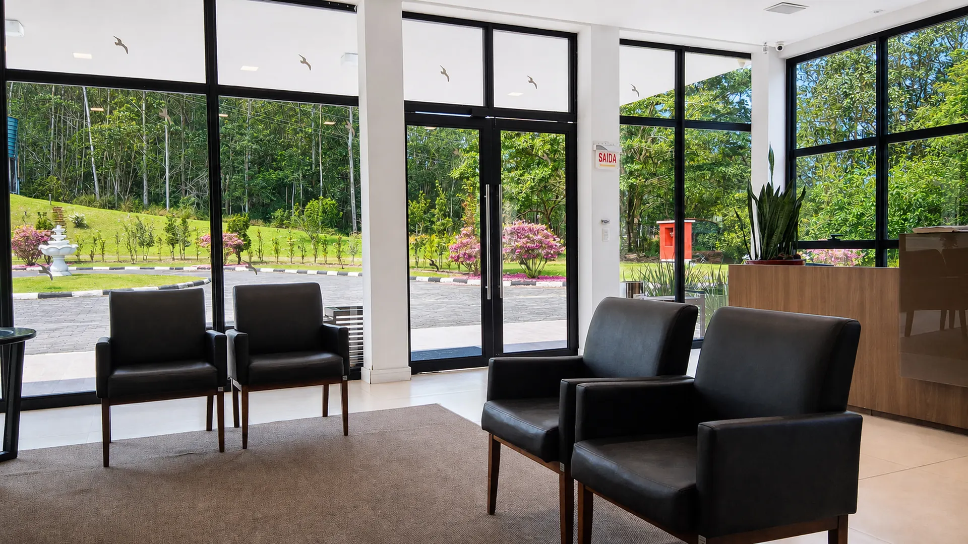 Sala de espera da Nova Belluno com janelões voltados para a mata